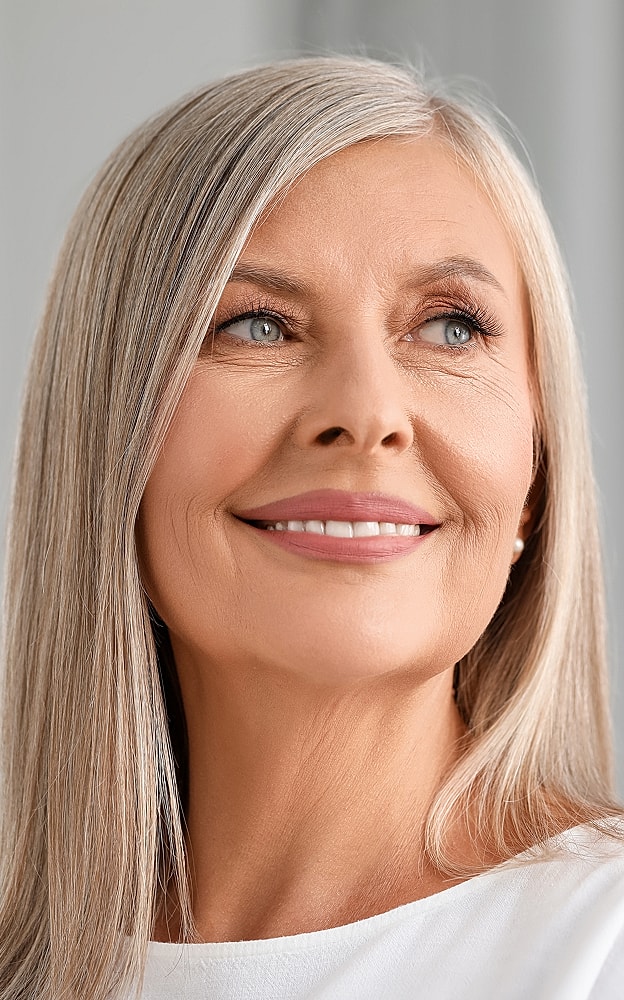 Smiling Lafayette facial plastic surgery model with long silver hair.